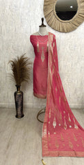 Pink saree with gold patterns on a mannequin against a light gray wall.