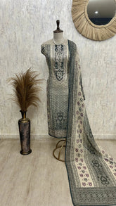 Mannequin wearing a traditional outfit with a patterned dupatta against a textured wall.