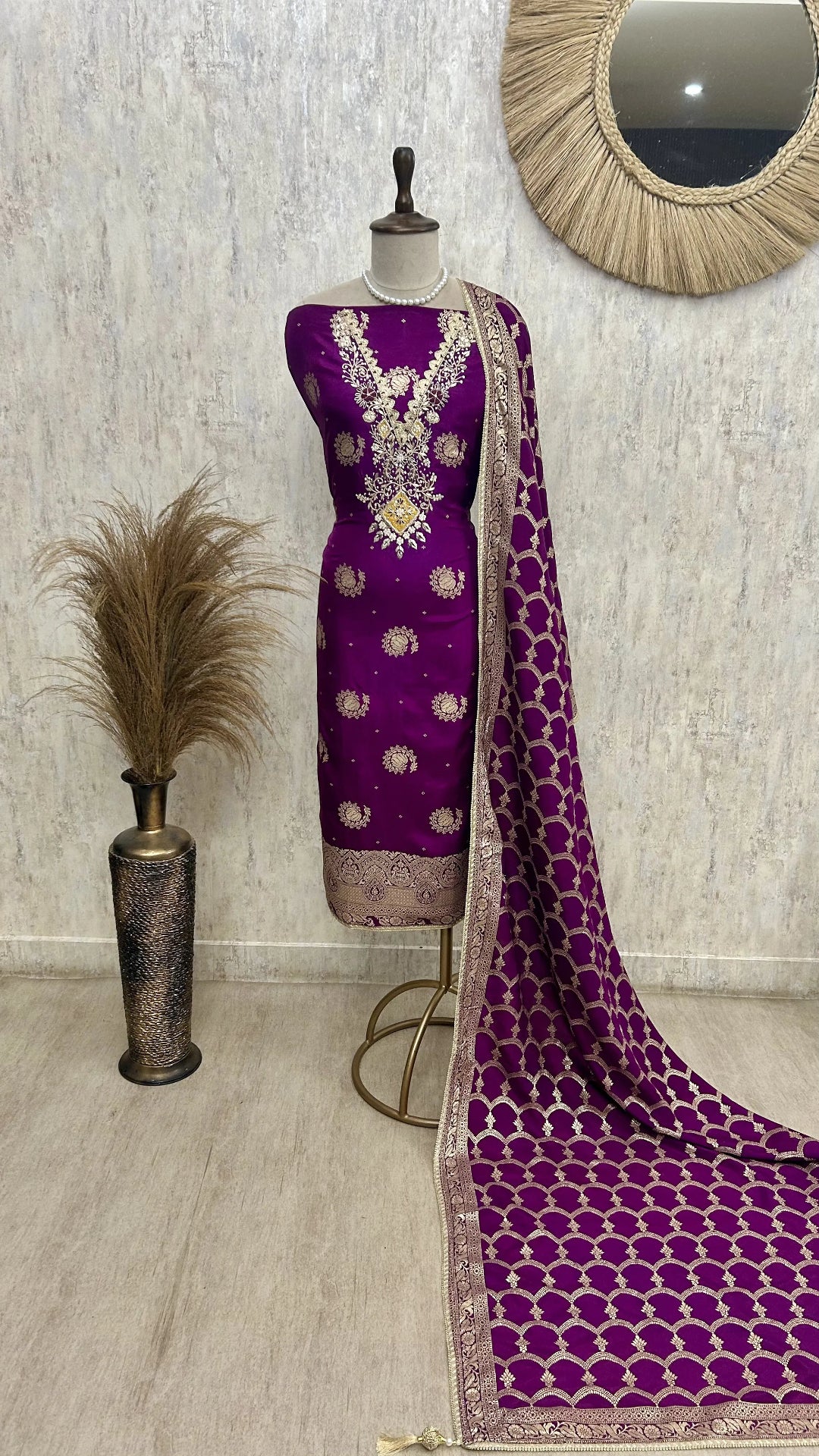 Purple saree with gold patterns on a mannequin against a neutral wall.