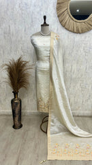 Mannequin wearing a white saree with a floral pattern against a textured wall.