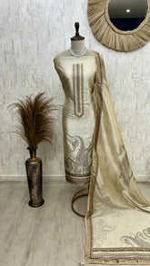 Mannequin wearing a cream-colored embroidered dress with a matching dupatta against a light gray wall.