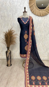 Navy blue embroidered dress with a matching dupatta on a mannequin against a textured wall.