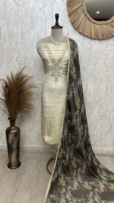 Mannequin wearing a cream saree with a floral patterned dupatta against a textured wall.