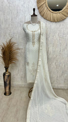 White embroidered dress on a mannequin with a decorative mirror and vase in the background.