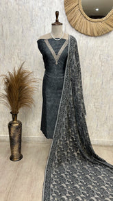 Gray saree with a patterned border on a mannequin against a textured wall.
