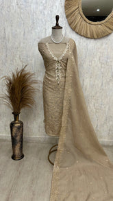 Beige embroidered dress on a mannequin with a mirror and decorative vase in the background