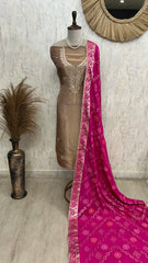 Mannequin wearing a brown dress with a pink saree draped over it against a neutral wall.