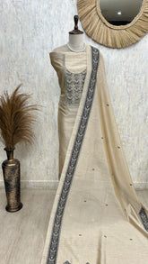 Mannequin wearing a cream saree with black border against a textured wall.