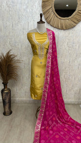 Yellow dress with pink dupatta on a mannequin against a neutral wall.