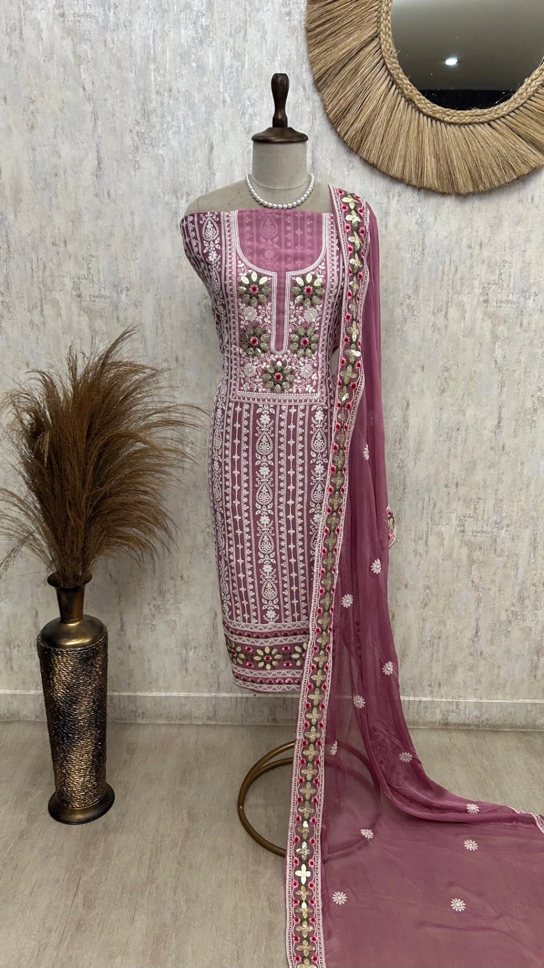 Pink embroidered traditional outfit on a mannequin with a neutral background