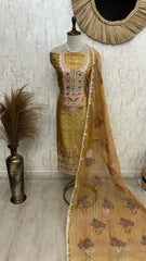 Gold embroidered traditional outfit on a mannequin with a textured wall background