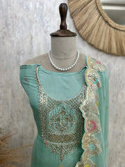 Light blue embroidered garment on a mannequin with a pearl necklace against a neutral background