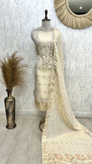 Mannequin wearing a cream saree with floral patterns against a light gray wall.
