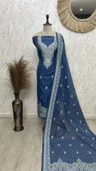 Blue embroidered dress on a mannequin with a decorative mirror and plant in the background