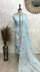 Light blue embroidered fabric on a mannequin against a textured wall.