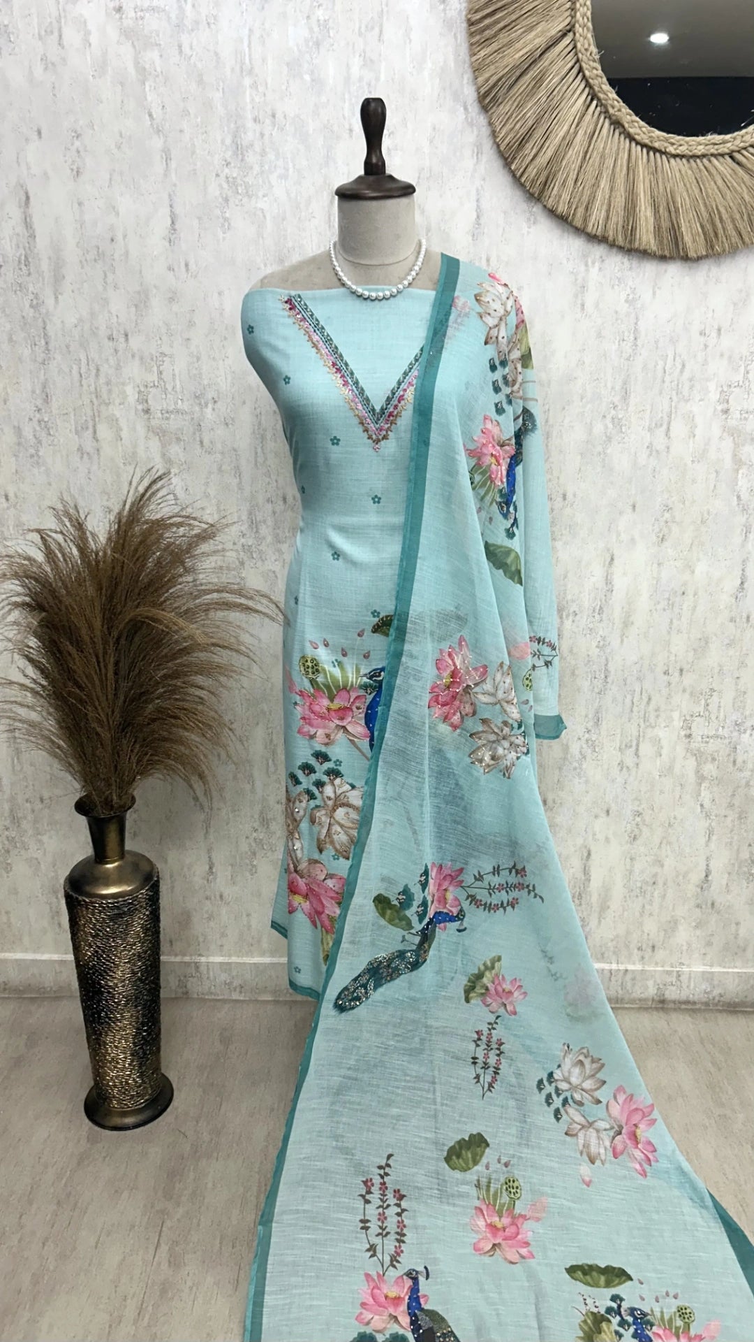 Light blue embroidered dress with floral patterns on a mannequin against a white wall.
