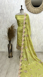 Green saree with floral patterns on a mannequin against a neutral background