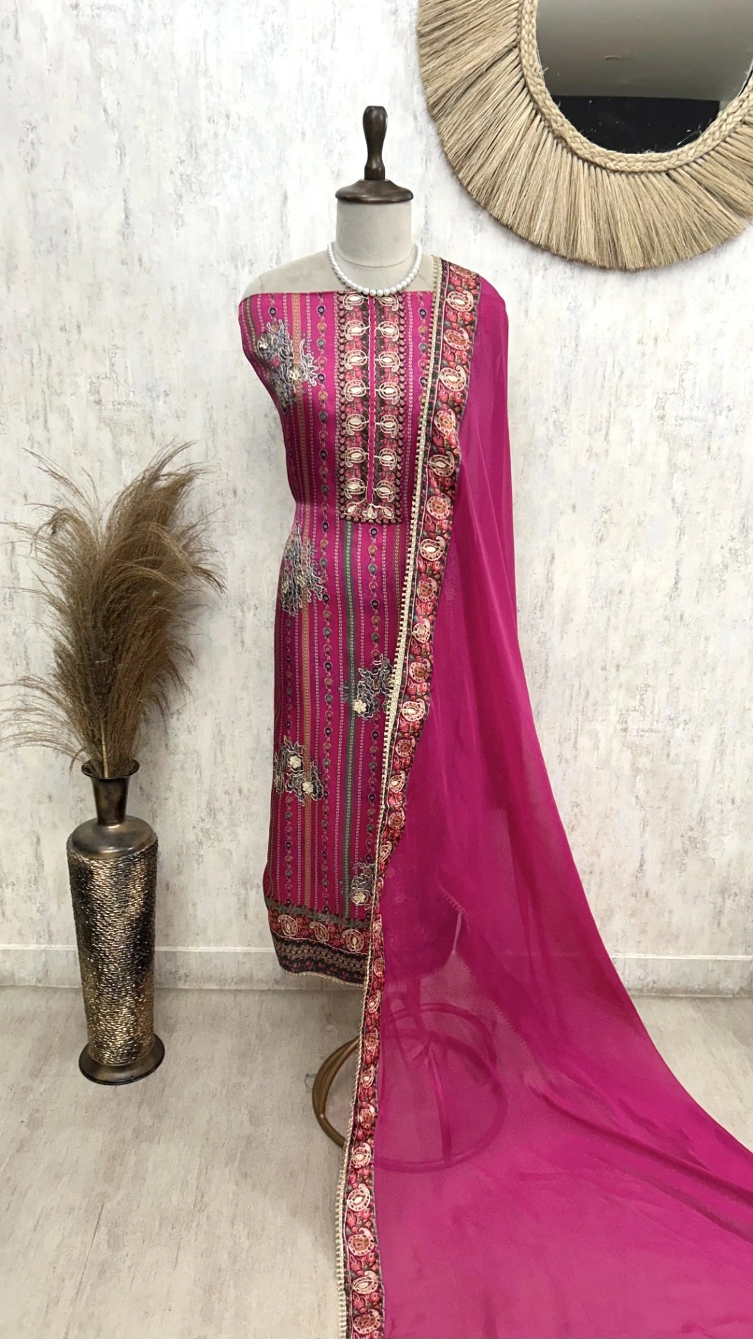 Pink traditional outfit with embroidery on a mannequin against a white wall.