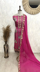 Pink traditional outfit with embroidery on a mannequin against a white wall.