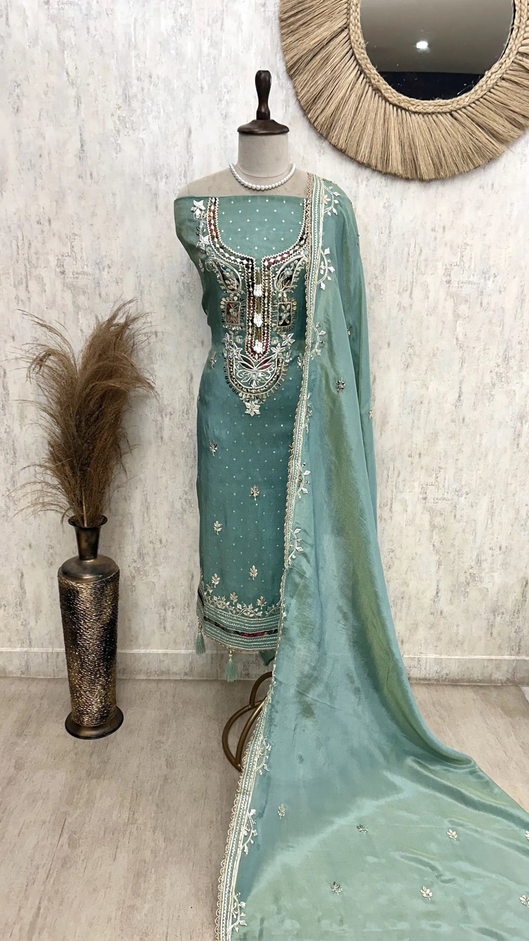 Teal embroidered traditional outfit with dupatta on a mannequin against a light background