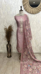 Mauve embroidered traditional outfit on a mannequin with a decorative mirror and vase in the background.