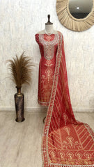 Red embroidered traditional outfit with a matching dupatta on a mannequin against a neutral wall.
