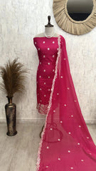 Pink saree with white patterns on a mannequin against a white wall.