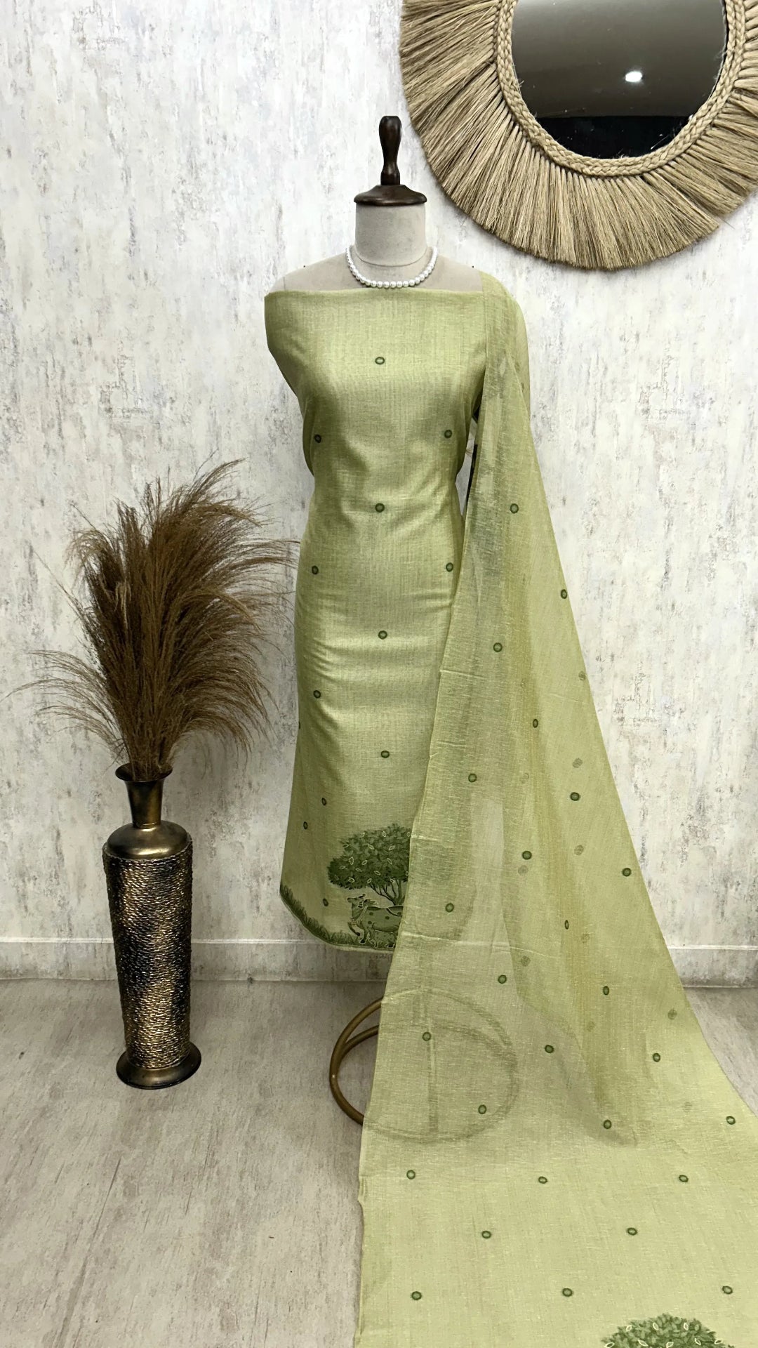 Green saree with a matching blouse on a mannequin against a white wall.