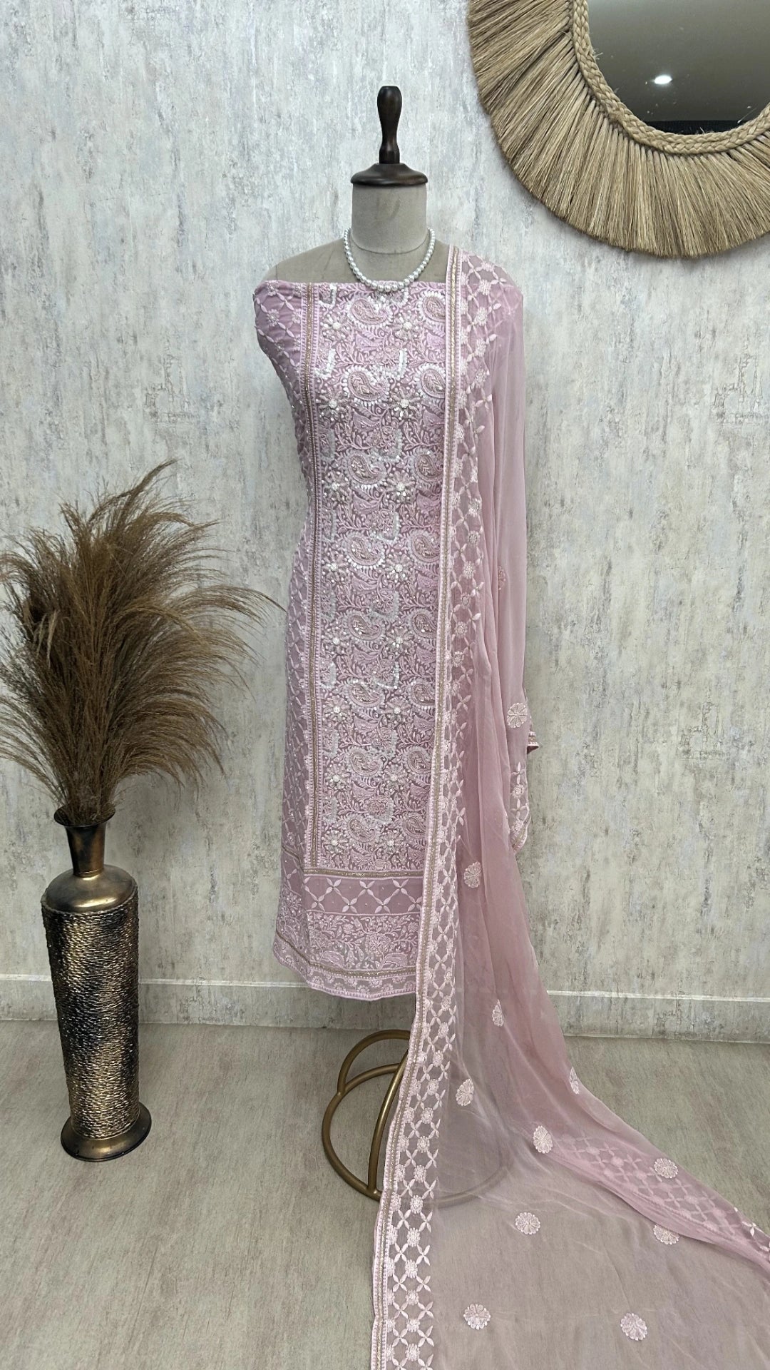 “Dusty pink georgette unstitched suit set with delicate white floral embroidery and pearl detailing, paired with sheer matching dupatta on mannequin.”