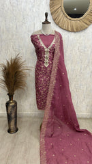 Mauve embroidered saree with a mannequin against a neutral wall.